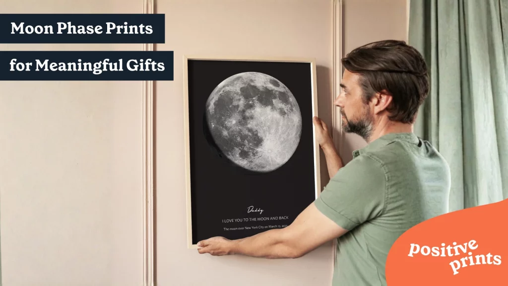 Man hanging a framed personalized moon phase print on the wall with the text “Moon Phase Prints for Meaningful Gifts”